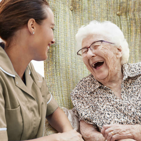 old white woman african american caregiver seated laughing
